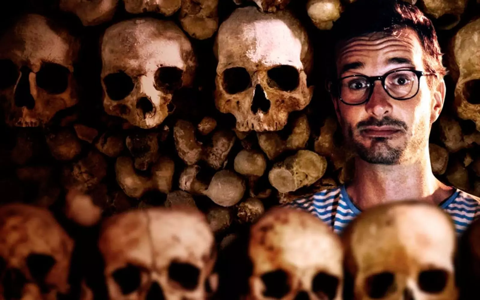 David Farrier omringd door schedels.