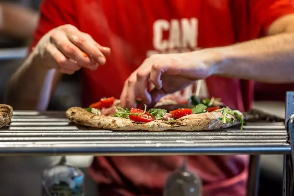 Umieszczanie składników pizzy w Can Pizza.