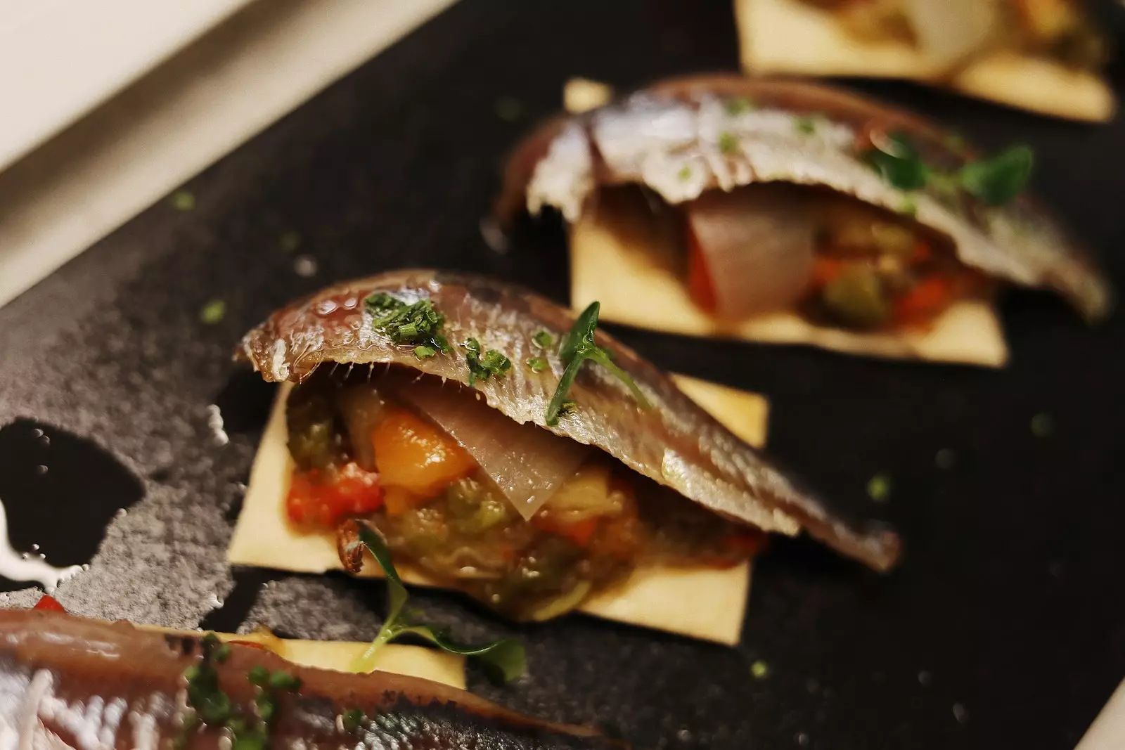 Coca de recapte do restaurante Cadaqus, uma base fina de coca coberta com legumes assados e uma sardinha de anchova.