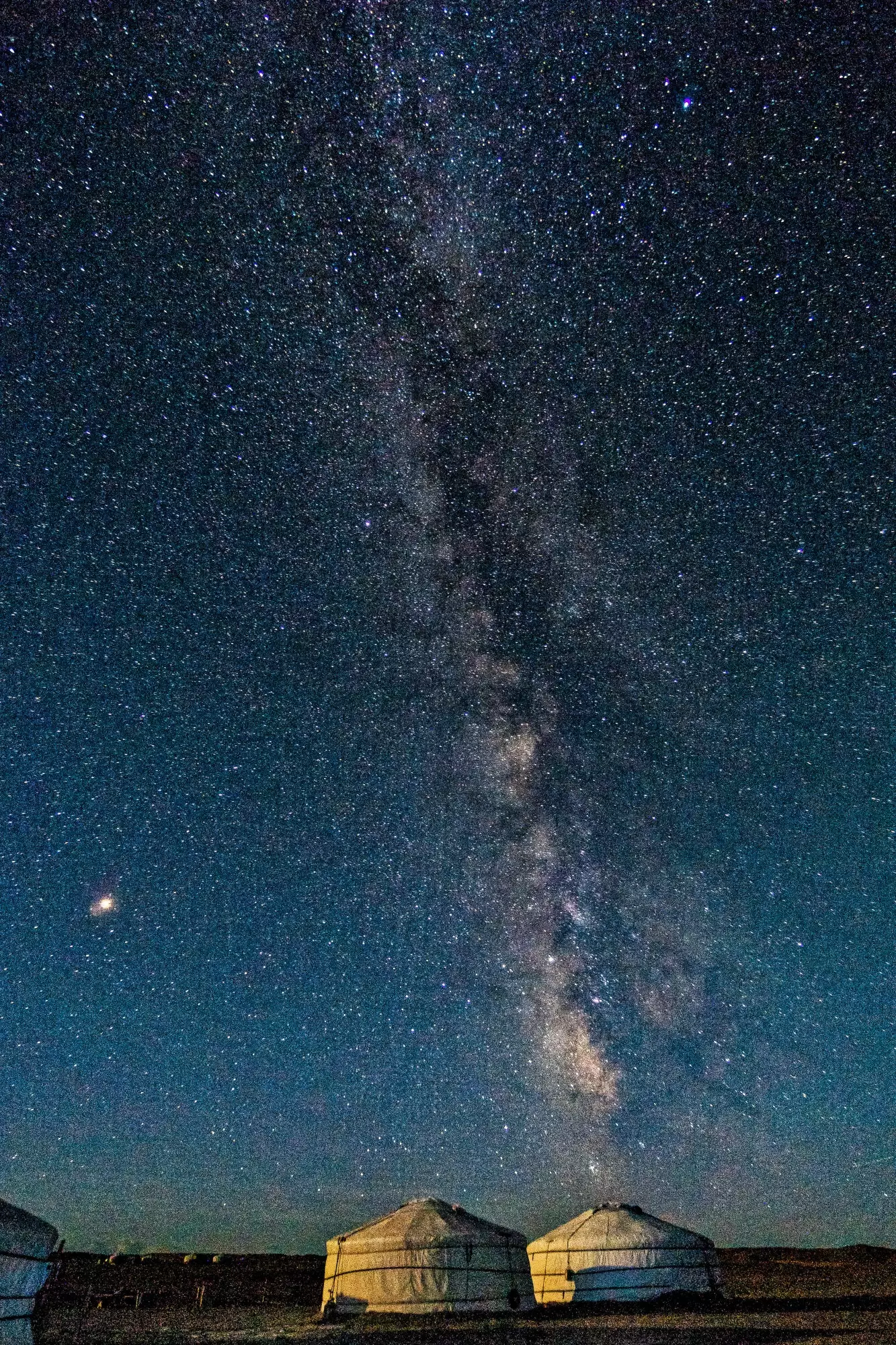 Bima Sakti di atas beberapa yurt di tebing yang menyala di Gurun Gobi.