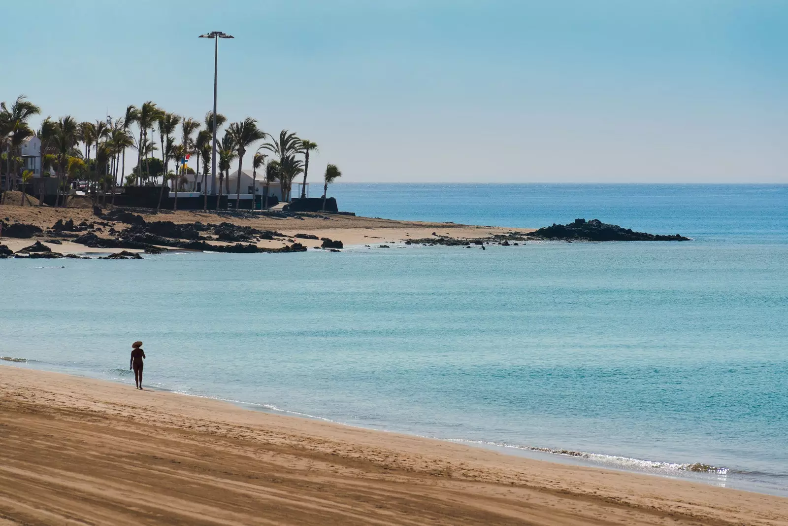 Berjalan bersendirian di sepanjang Playa Grande Puerto del Carmen Tías di Lanzarote.