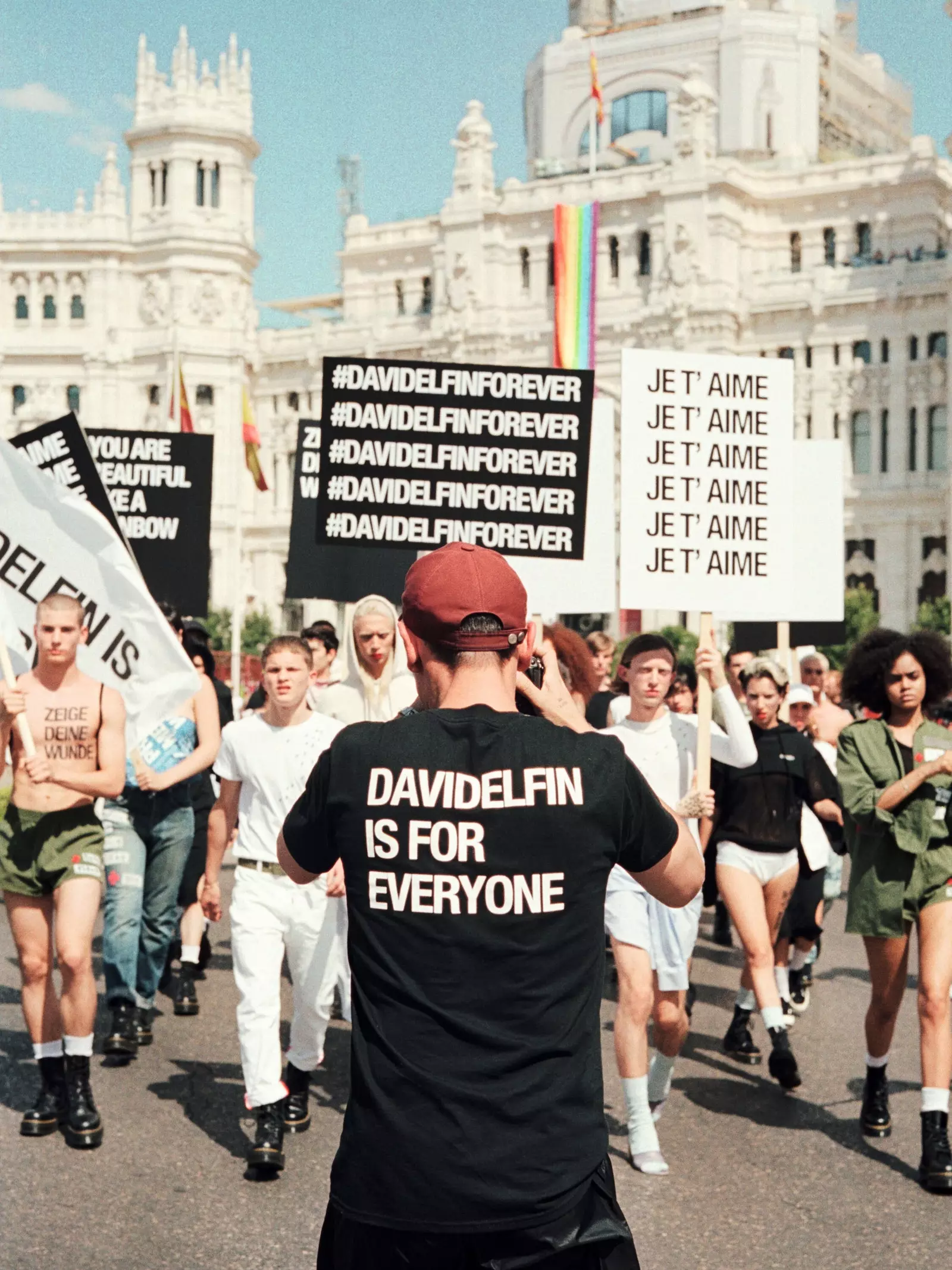 Grup de persones desfila amb pancartes d'homenatge a David Delfín després de la seva mort davant del Palau de Cibeles...