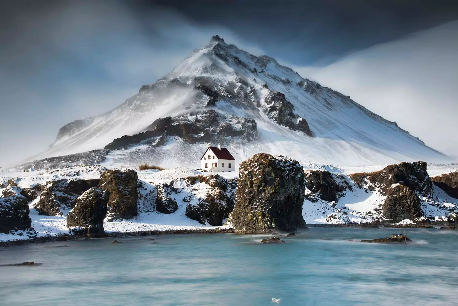 snow mountain with sea and a house