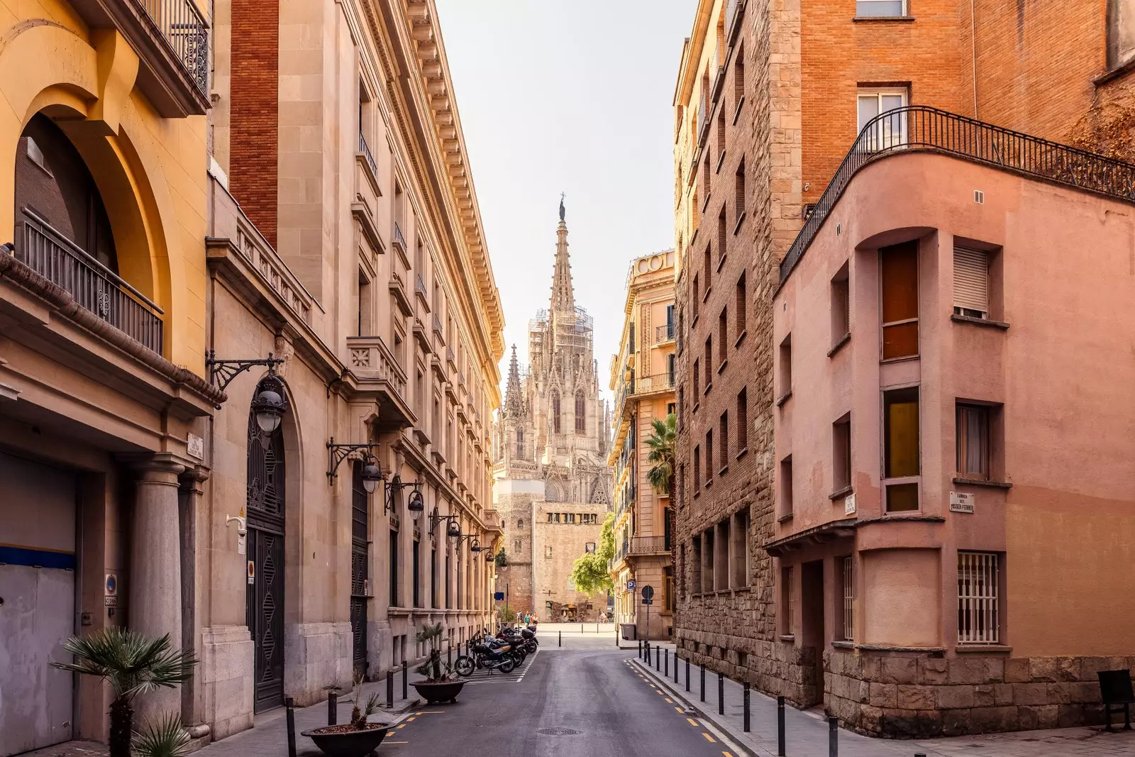 Die Sagrada Familia im Hintergrund einer Straße mit erdigen Fassaden im gotischen Viertel von Barcelona