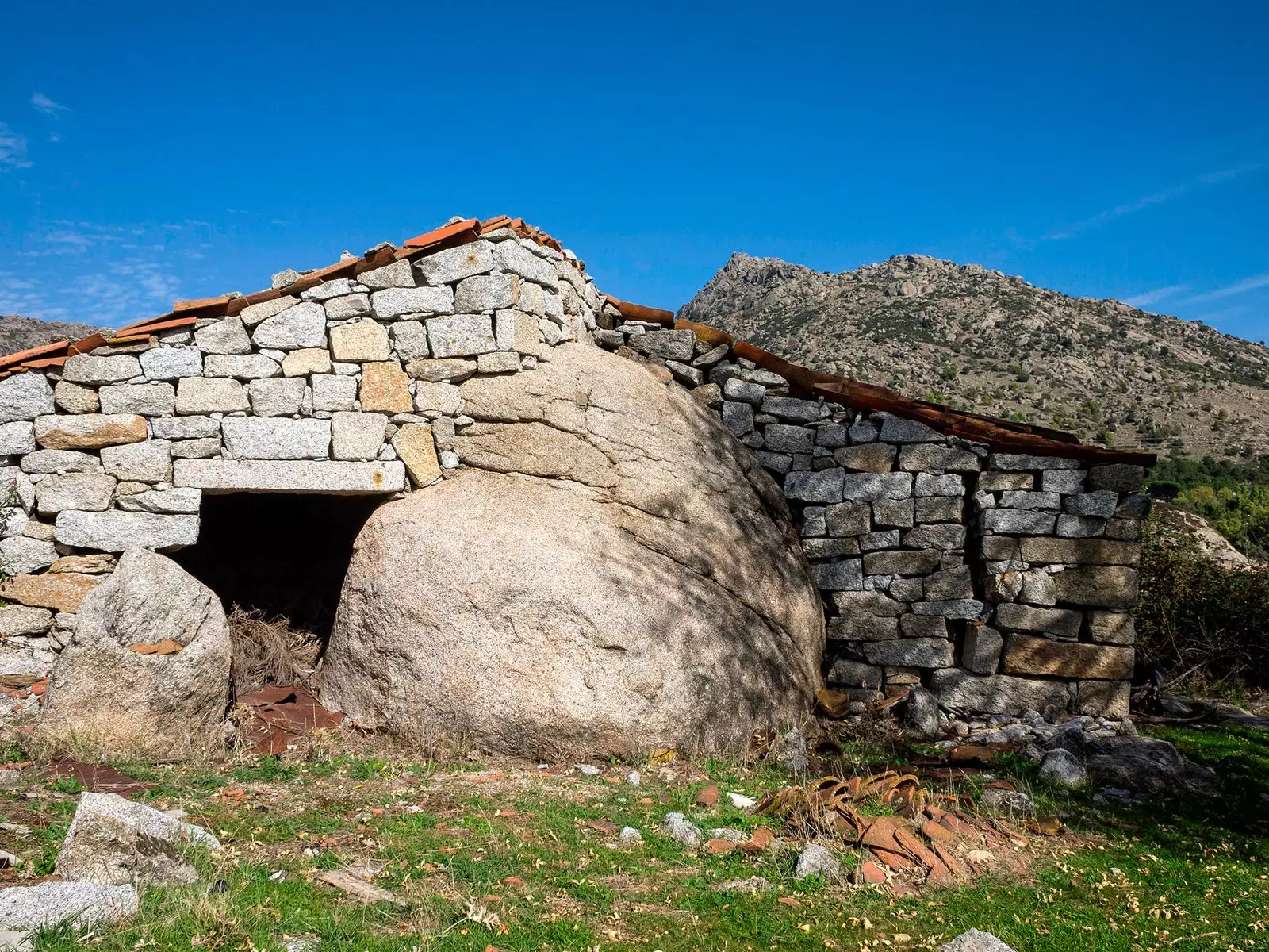 Old stone house with La Machota in the background in Zarzalejo Madrid