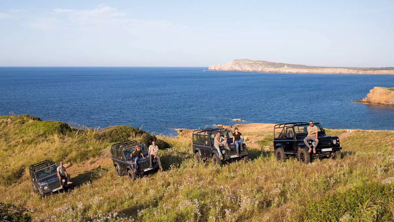 Fire jeeps står foran havet på Menorca.