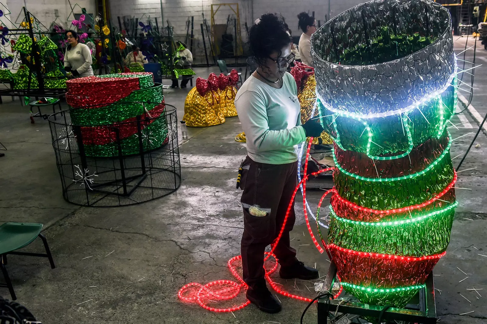 Oibríonn bean ag ullmhú soilsiú na Nollag i Medellín