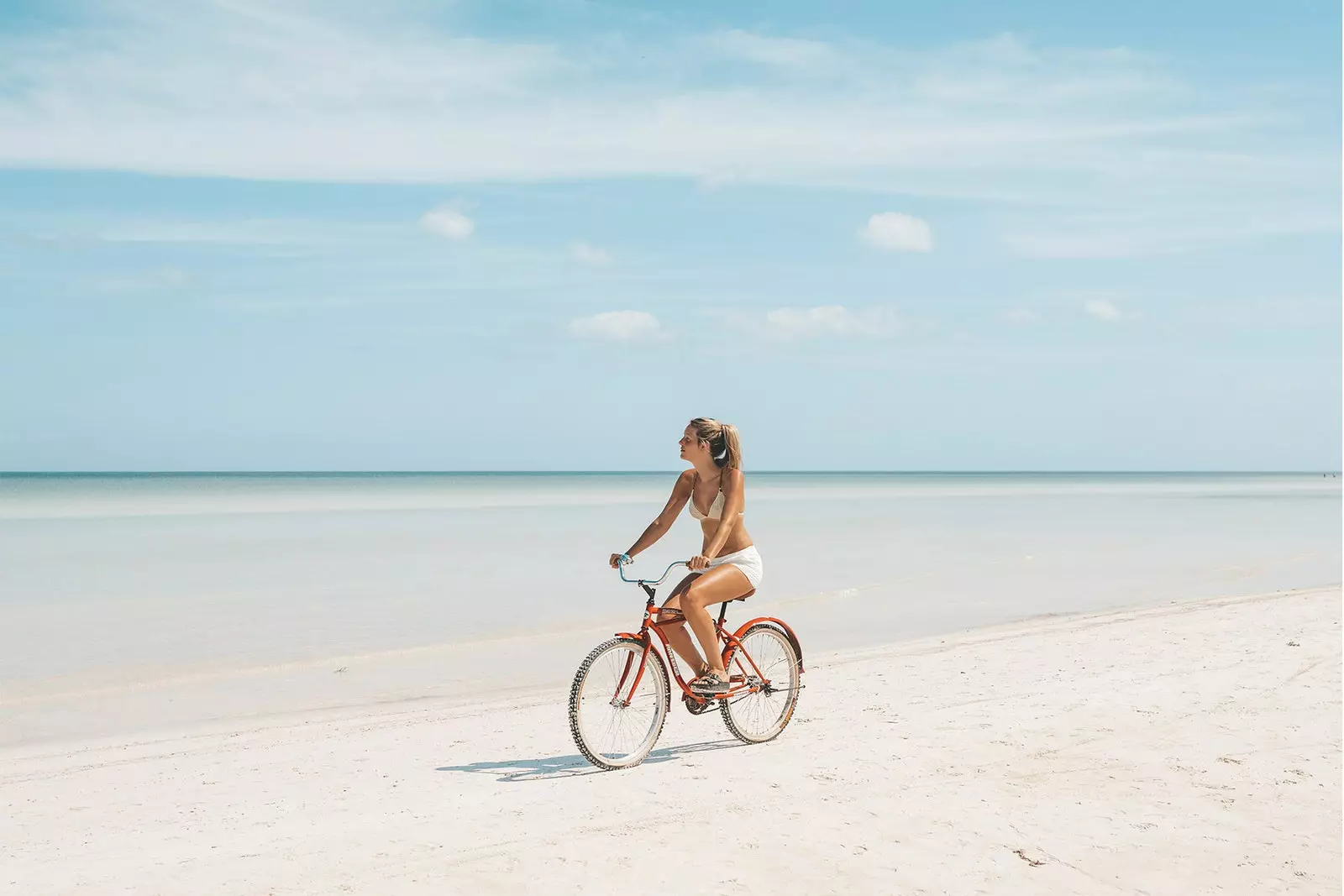 MÄDCHEN AUF EINEM FAHRRAD AUF DEM STRAND