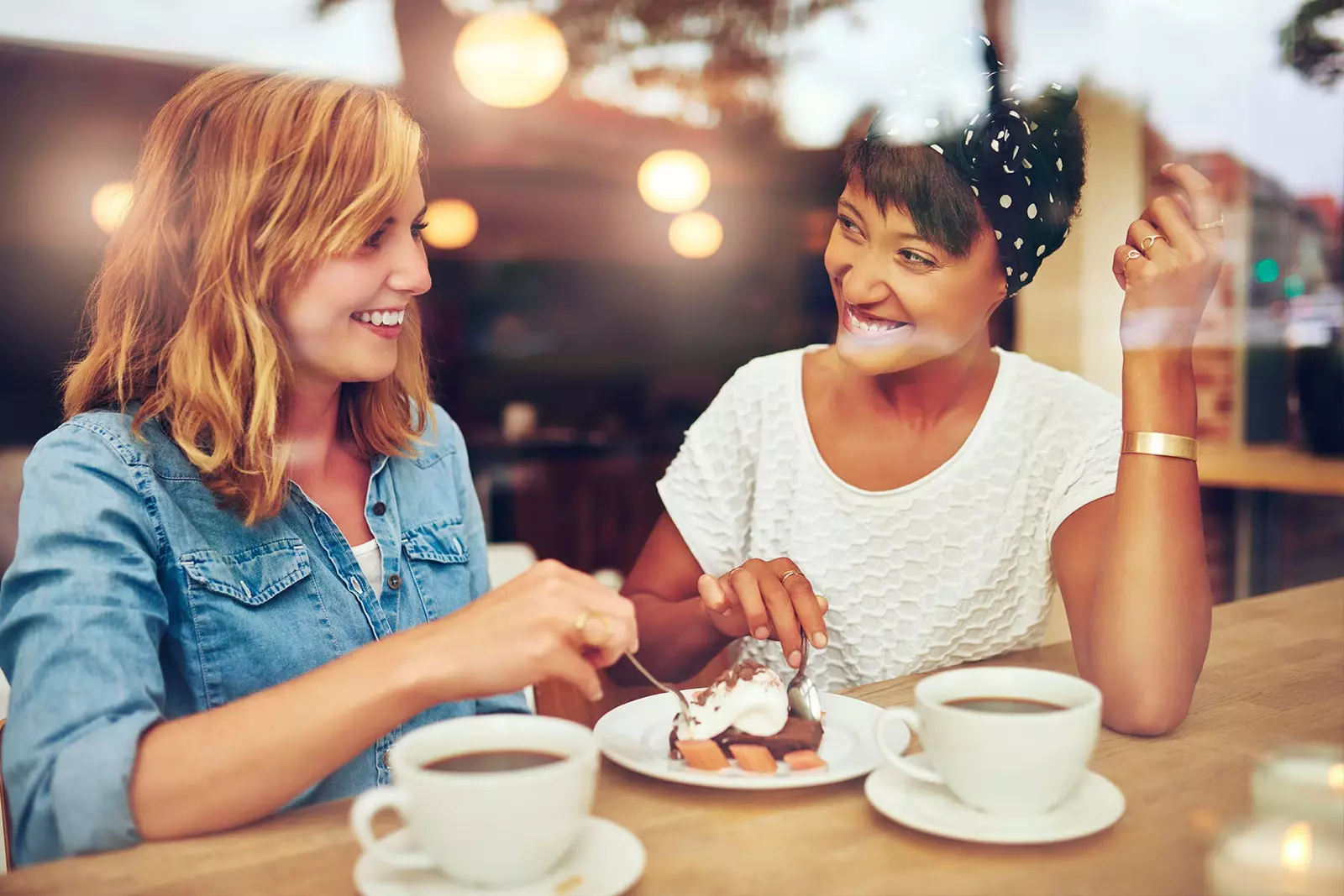 dues amigues prenent cafe i menjant pastís