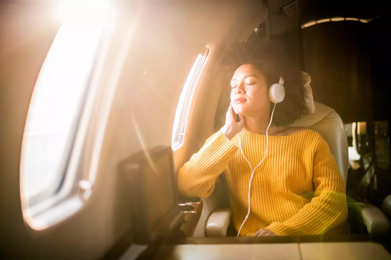 Mulher relaxa ouvindo música no avião.