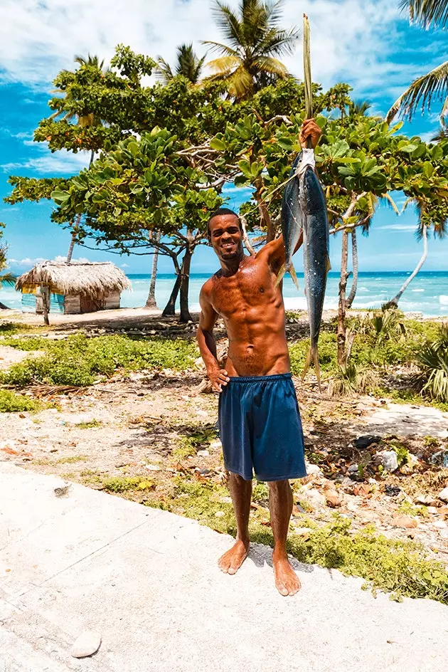 En ung dominikan kommer från fiske för att sälja sin fångst