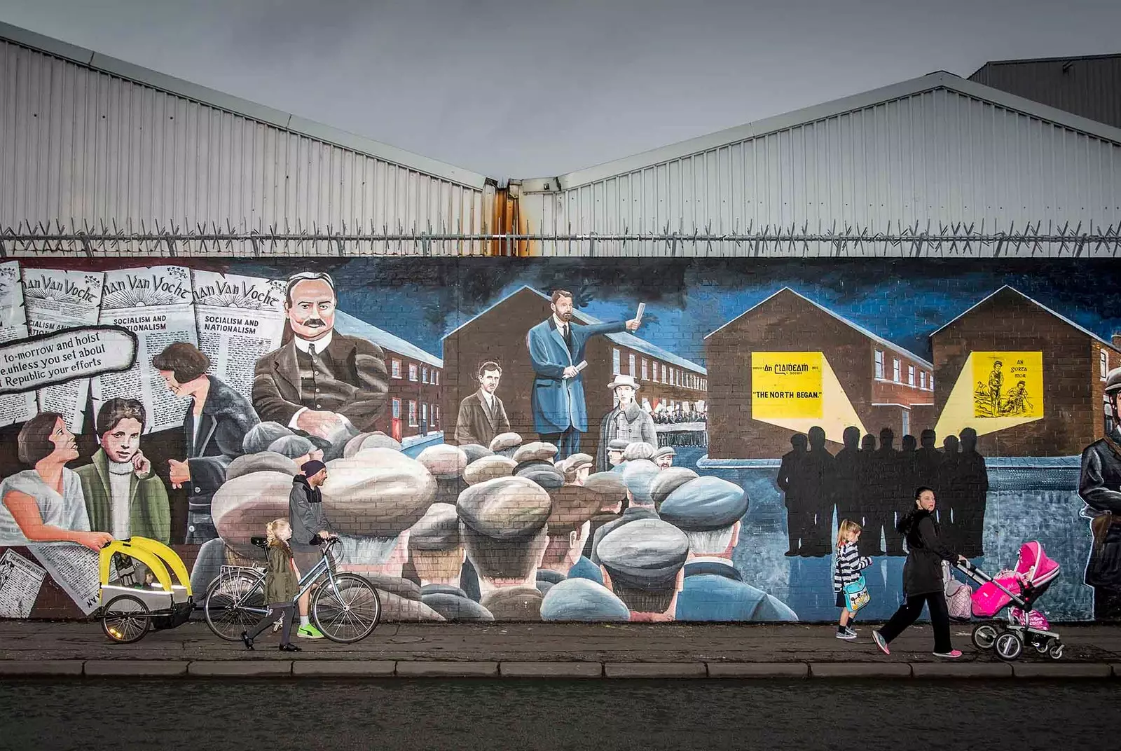 mensen lopen langs een muurschildering in belfast