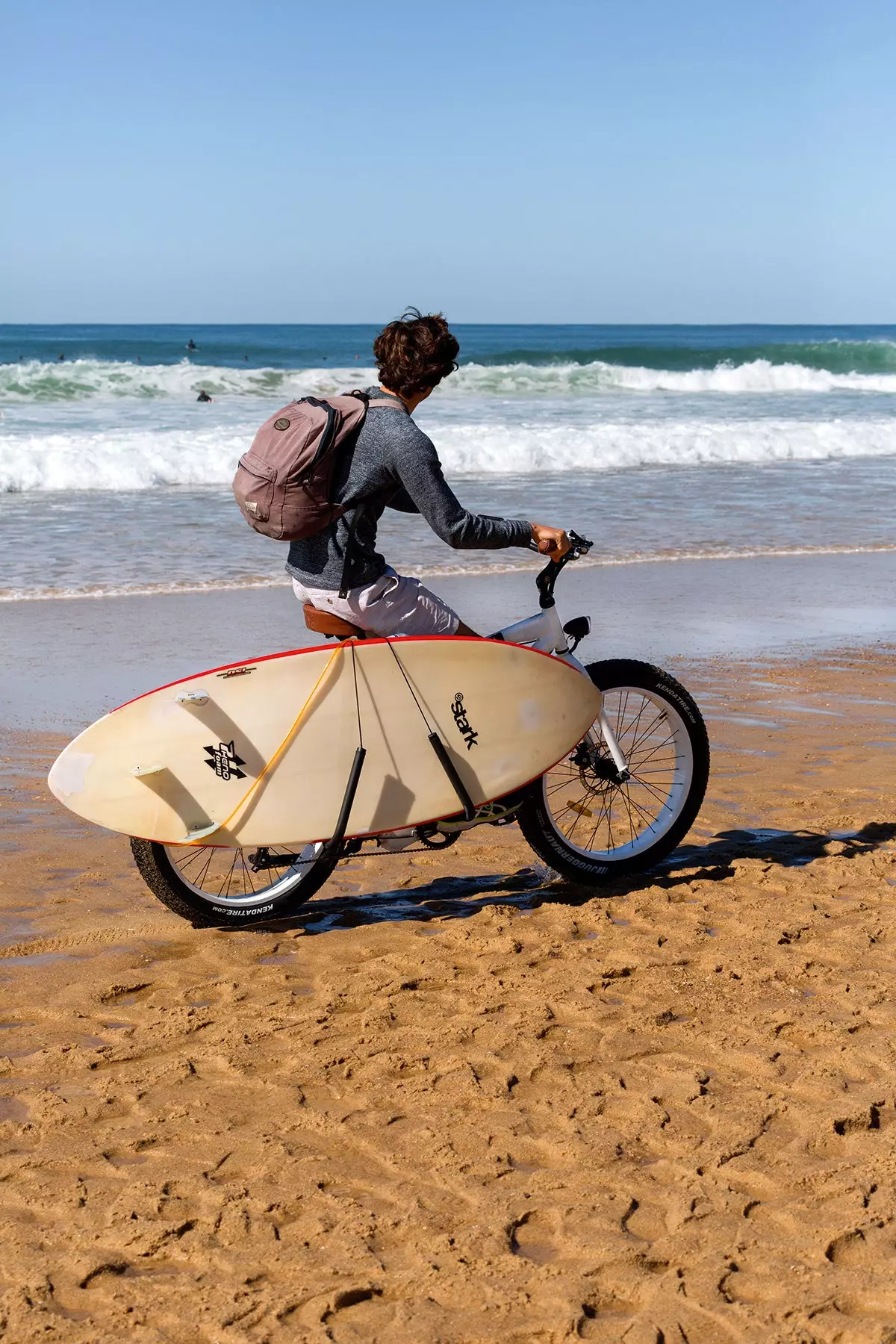 Un surfeur cycliste se promenant sur la plage