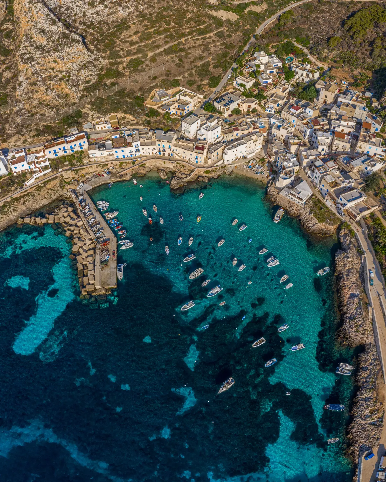 Amharc ón aer ar oileán Favignana le báid sa chuan agus an calafort