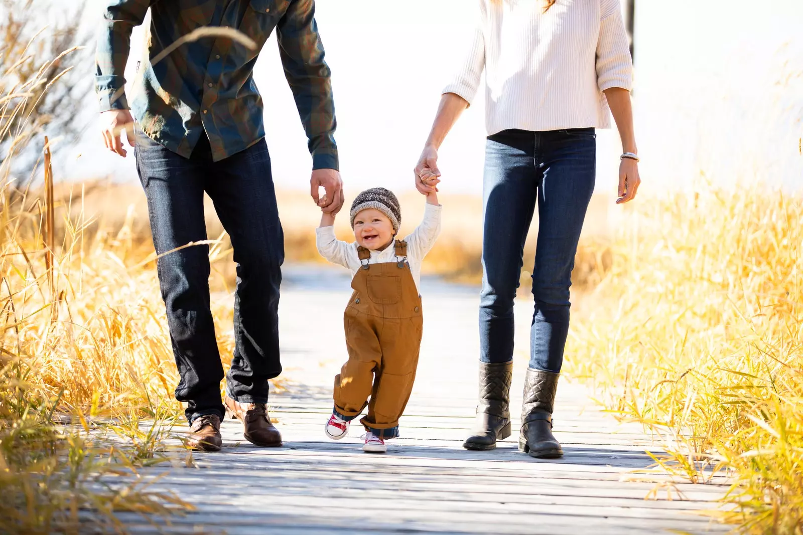 bayi berjalan berpegangan tangan dengan ibu bapanya